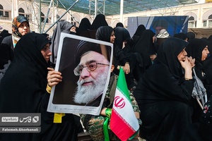 بانویی به همراه پسر نوجوان خود که در مراسم ارتحال امام خمینی (ره) شرکت کرده پوستر رهبر انقلاب را در دست دارد