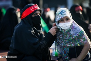 مادری در حال کامل کردن حجاب دختر خود در اجتماع بزرگ زنان عاشورایی  در میدان امام حسین(ع)